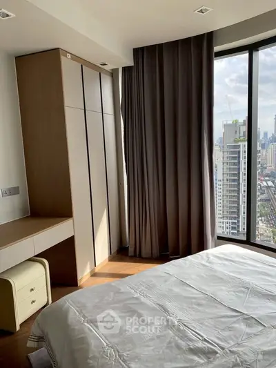 Modern bedroom with city view, featuring large windows and sleek furnishings in a high-rise apartment.