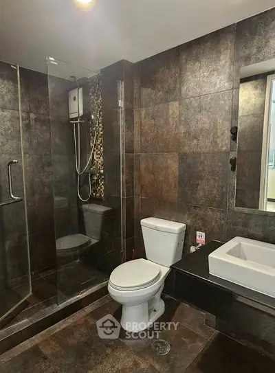 Modern bathroom with sleek design, featuring glass shower, stylish tiles, and contemporary fixtures.