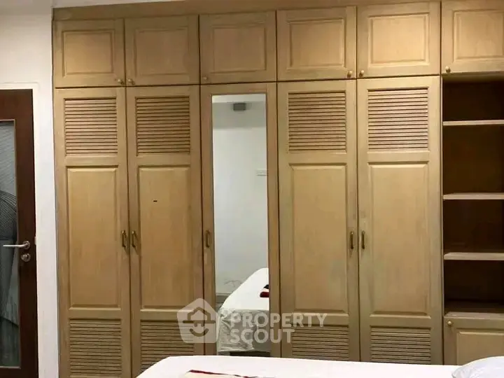 Spacious bedroom with built-in wooden wardrobes and mirror