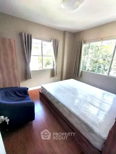 Bright bedroom with large windows and cozy furnishings in a modern home.
