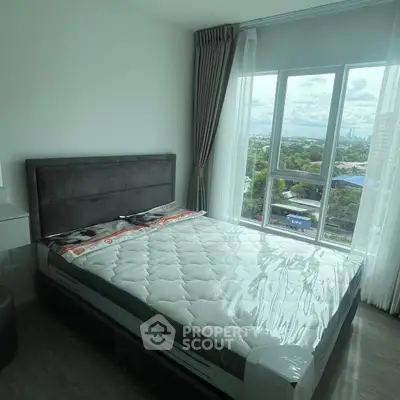 Modern bedroom with large window offering scenic city view, featuring a new mattress and stylish decor.