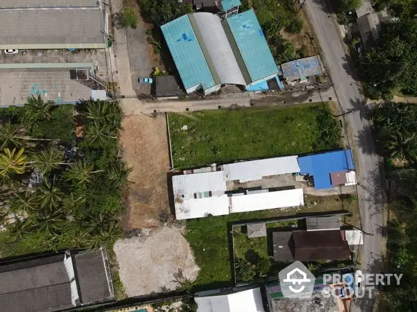 Aerial view of a vacant lot in a residential area, surrounded by houses with potential for development, showcasing the neighborhood layout and greenery.