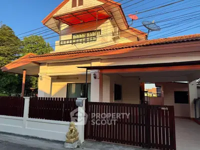 Charming two-story house with red roof and gated entrance in a serene neighborhood.
