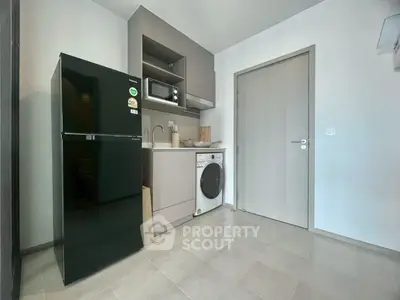 Modern compact kitchen with black fridge, microwave, and washing machine