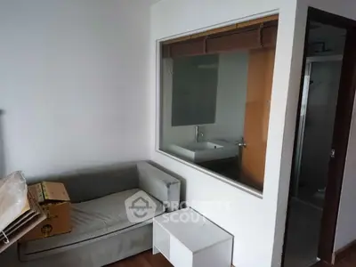 Compact living space with a sofa, window view into bathroom, and minimalistic decor.