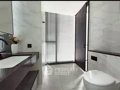 Modern bathroom with sleek design and marble finishes, featuring a stylish sink and toilet.