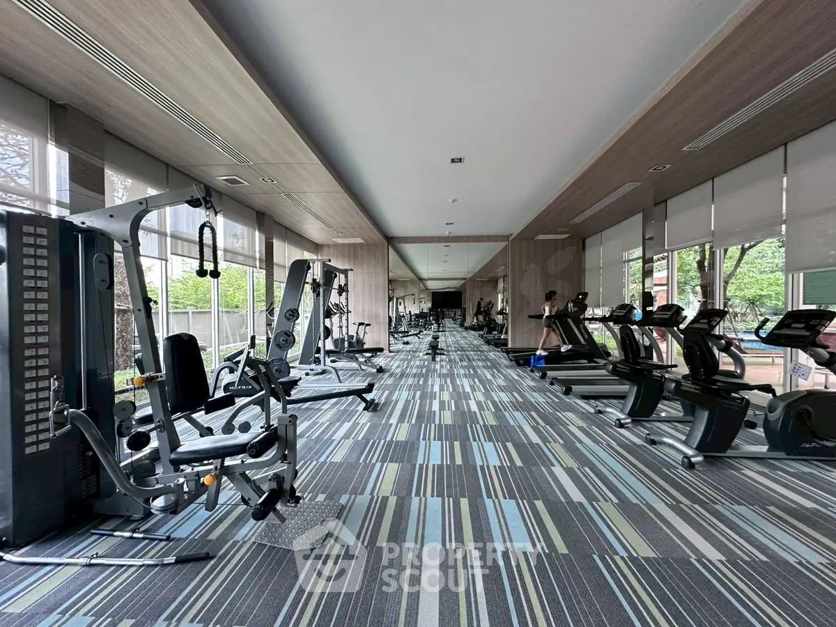 Spacious modern gym with state-of-the-art equipment and large windows offering natural light.
