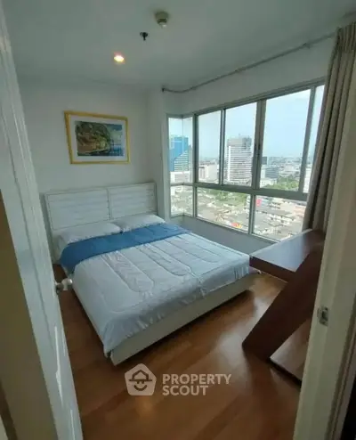 Bright bedroom with city view and modern furnishings in high-rise apartment.