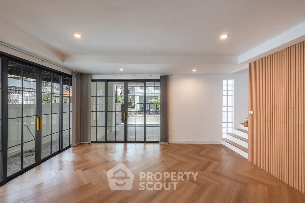 Spacious modern living room with large windows and stylish wood flooring.
