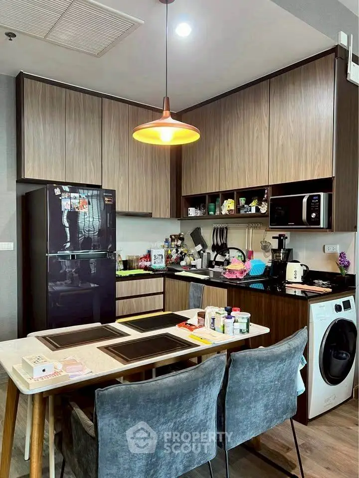 Modern kitchen with sleek cabinets, dining area, and appliances including fridge and washing machine.