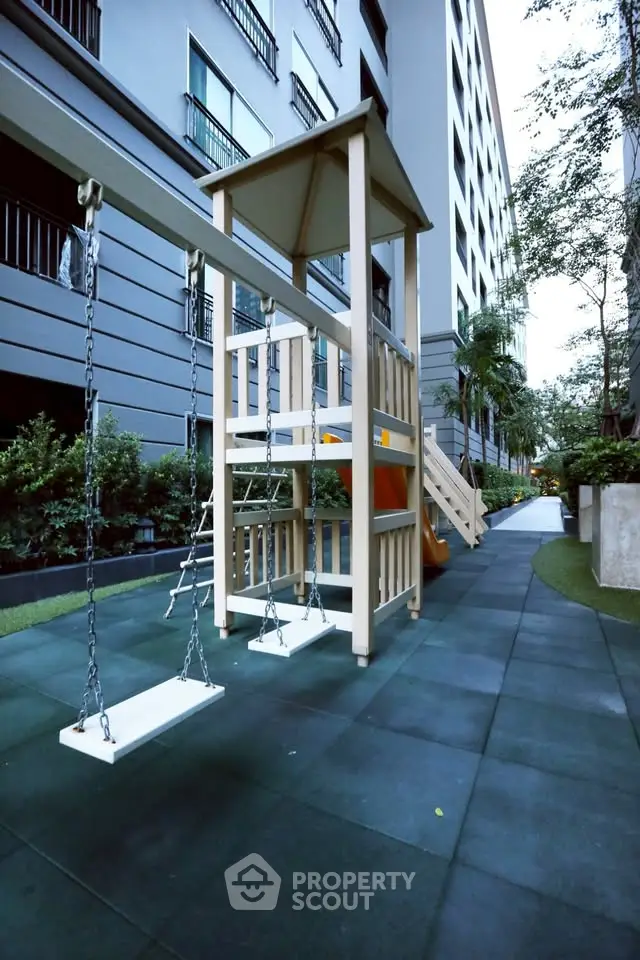 Modern apartment building with outdoor playground and lush greenery.