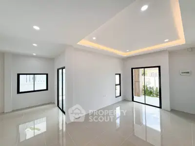 Spacious modern living room with large windows and sleek tile flooring.