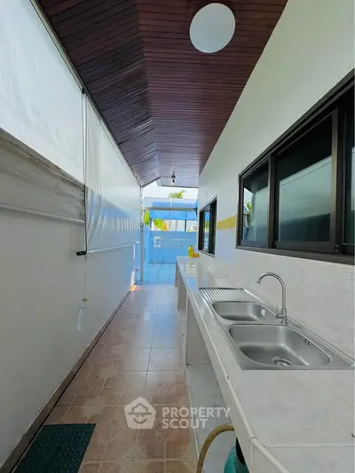 Charming outdoor kitchen area with dual sinks and tiled flooring, perfect for entertaining.
