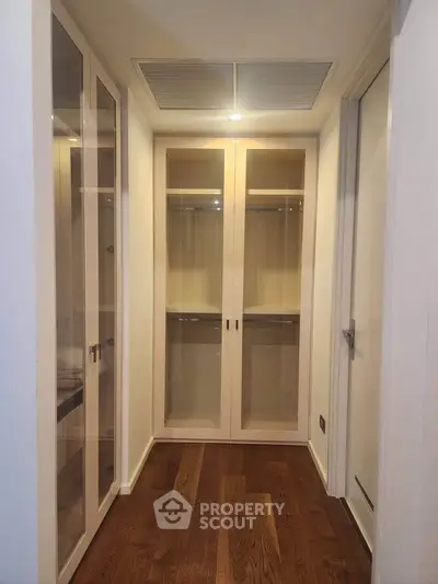 Spacious walk-in closet with elegant wooden flooring and ample storage space.