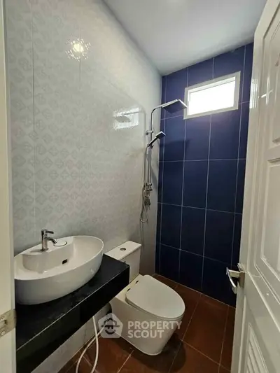 Compact modern bathroom with sleek fixtures and stylish blue accent wall.