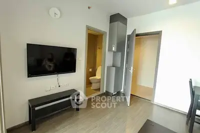 Modern living room with wall-mounted TV and open bathroom door, showcasing sleek design.