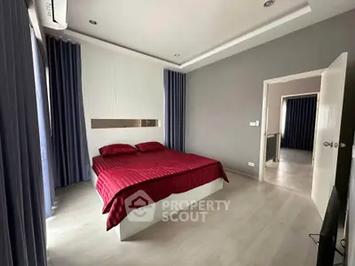 Modern bedroom with red bedding and elegant curtains in a stylish apartment.
