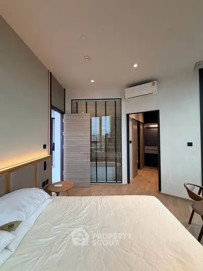 Modern bedroom with stylish decor and large window offering city view