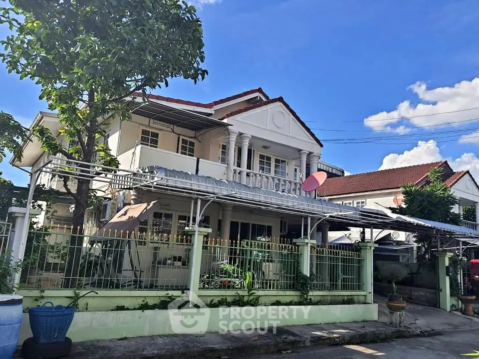 Charming two-story house with balcony and lush garden in a serene neighborhood.