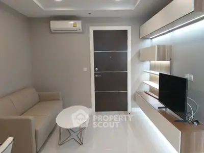 Modern living room with sleek furniture and wall-mounted TV in a stylish apartment.