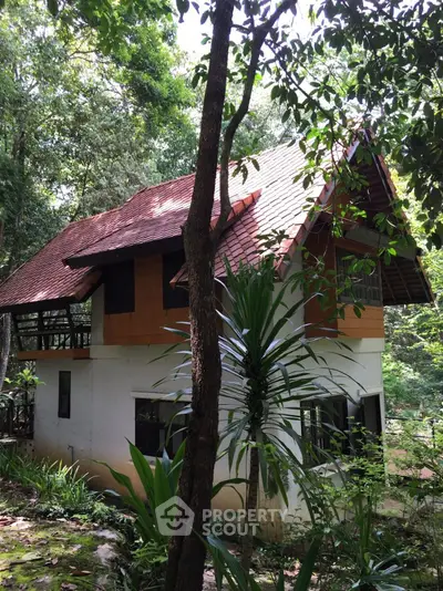 Charming two-story house nestled in lush greenery, perfect for nature lovers seeking tranquility.