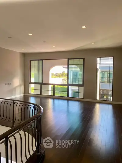 Spacious living room with large windows and elegant railing, offering a bright and airy atmosphere.
