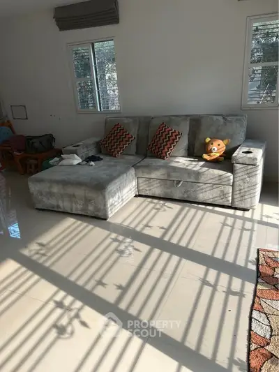 Spacious living room with plush gray sectional sofa and natural light from large windows.