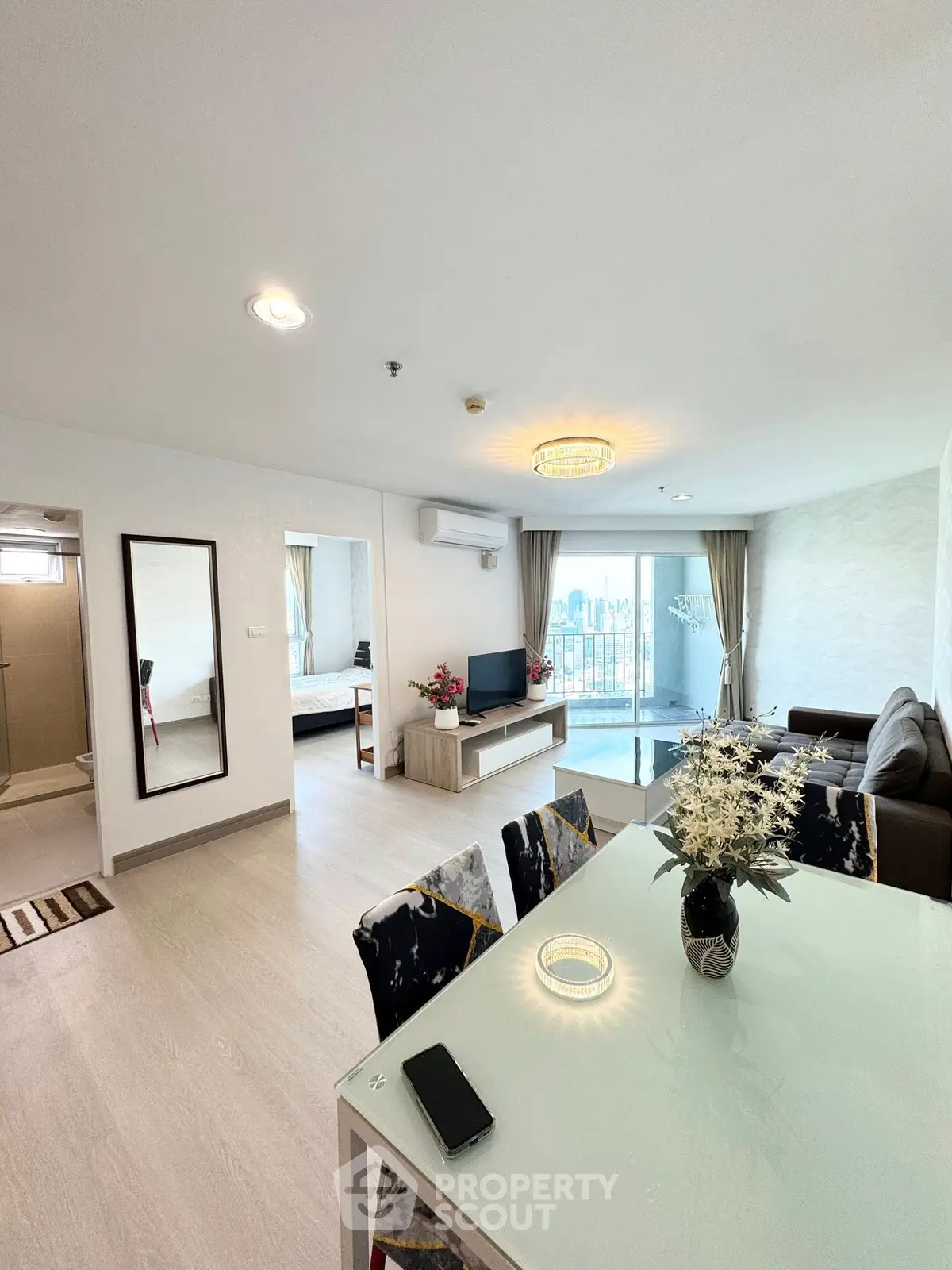 Spacious open-plan living room with modern decor and city view balcony.