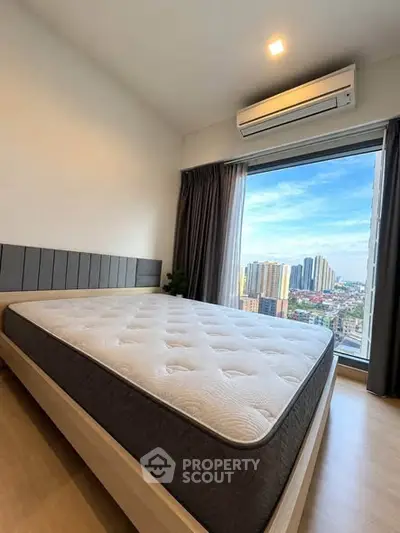 Modern bedroom with large window offering stunning city view and natural light.