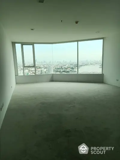 Spacious empty room with panoramic city view through large windows