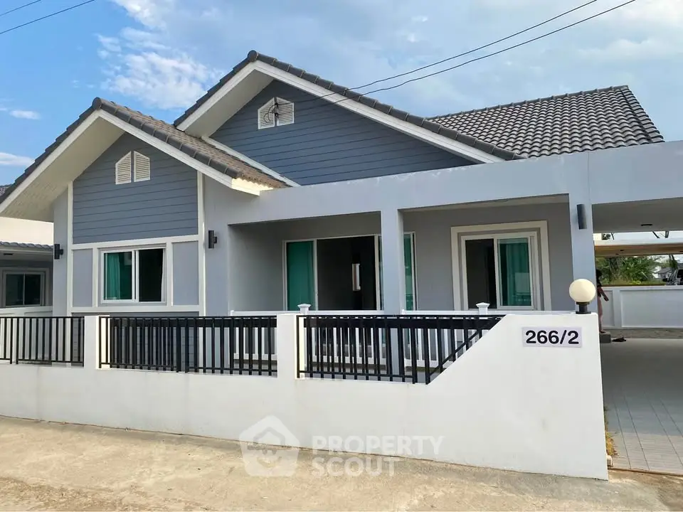 Charming modern house with blue siding and white accents, featuring a spacious carport and inviting entrance.
