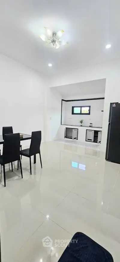 Modern open-layout kitchen and dining area with sleek black furniture and bright lighting.
