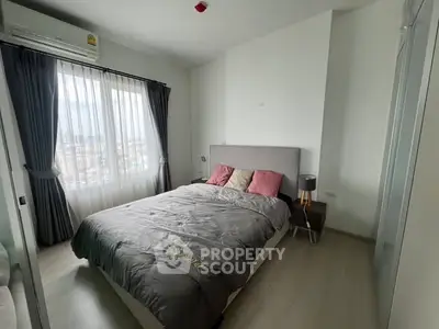 Modern bedroom with large window and stylish decor in urban apartment.