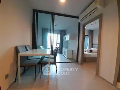Modern apartment interior with dining area and bedroom, featuring sleek furniture and bright lighting.