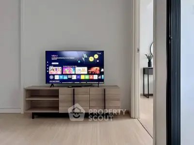 Modern living room with sleek TV stand and flat-screen TV, showcasing minimalist design and open space.