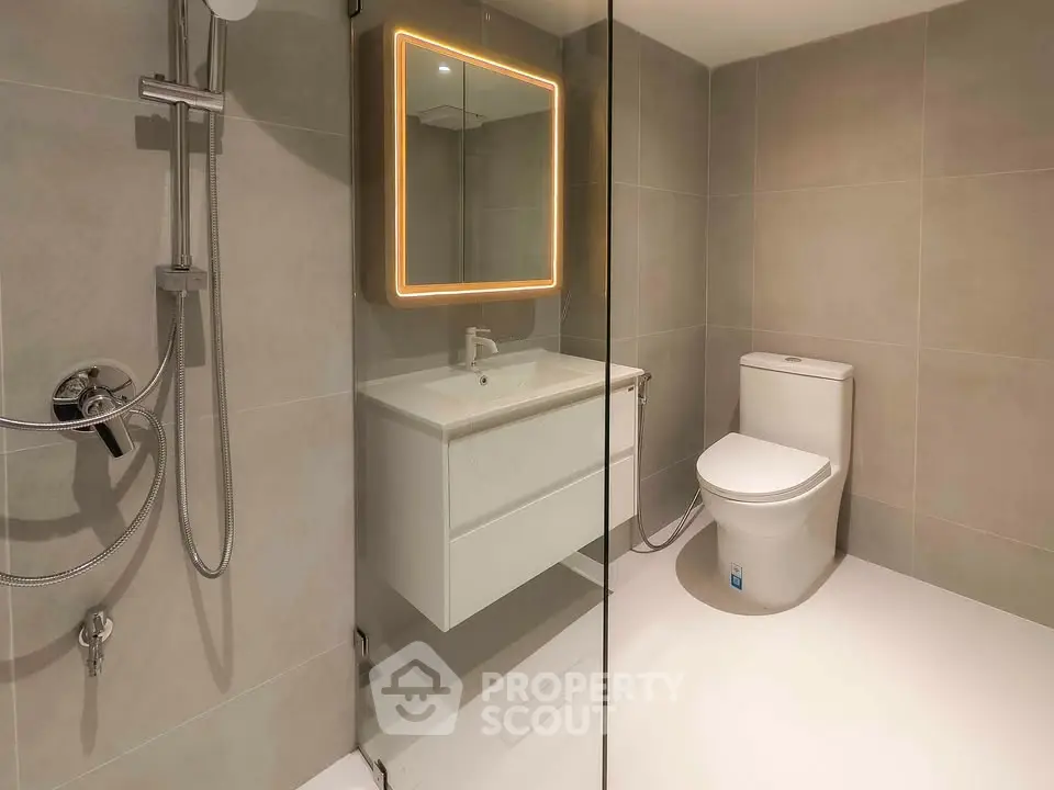 Modern bathroom with sleek fixtures and illuminated mirror in a contemporary home.