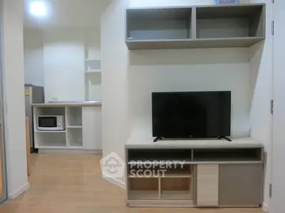 Modern living room with TV stand and open kitchen layout in cozy apartment.