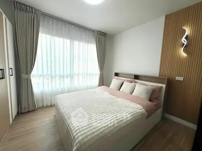 Modern bedroom with large window and stylish decor in a cozy apartment.