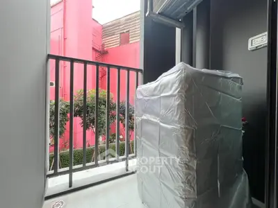 Compact balcony with washing machine and vibrant pink building view