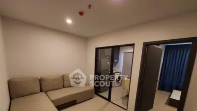 Modern living room with beige sofa and view into kitchen with washing machine