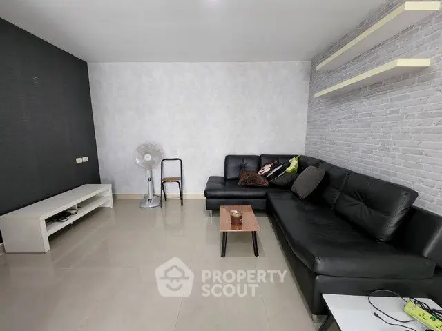 Spacious modern living room with sleek black leather sofa and minimalist decor.