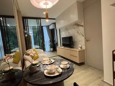 Modern living room with stylish decor and open layout, featuring a cozy dining area and large windows.
