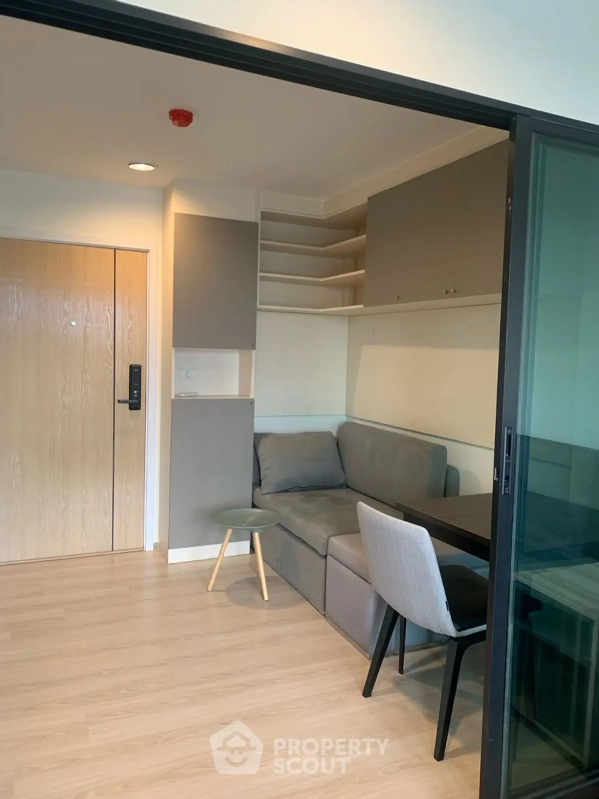 Modern compact living room with sliding glass door and cozy furniture.