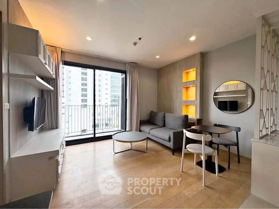 Modern living room with balcony view, stylish furniture, and natural light in urban apartment.