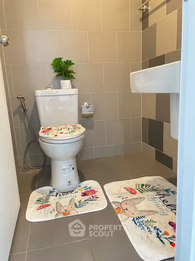 Charming bathroom with modern tiles and decorative mats, perfect for a cozy home ambiance.