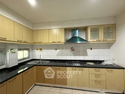 Spacious kitchen with modern cabinetry and gas stove, perfect for culinary enthusiasts.