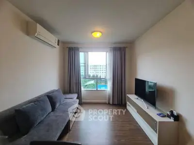 Modern living room with sleek furniture and large window offering a scenic view.