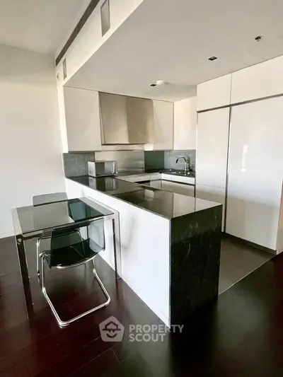 Modern kitchen with sleek black countertops and integrated appliances in a stylish apartment.