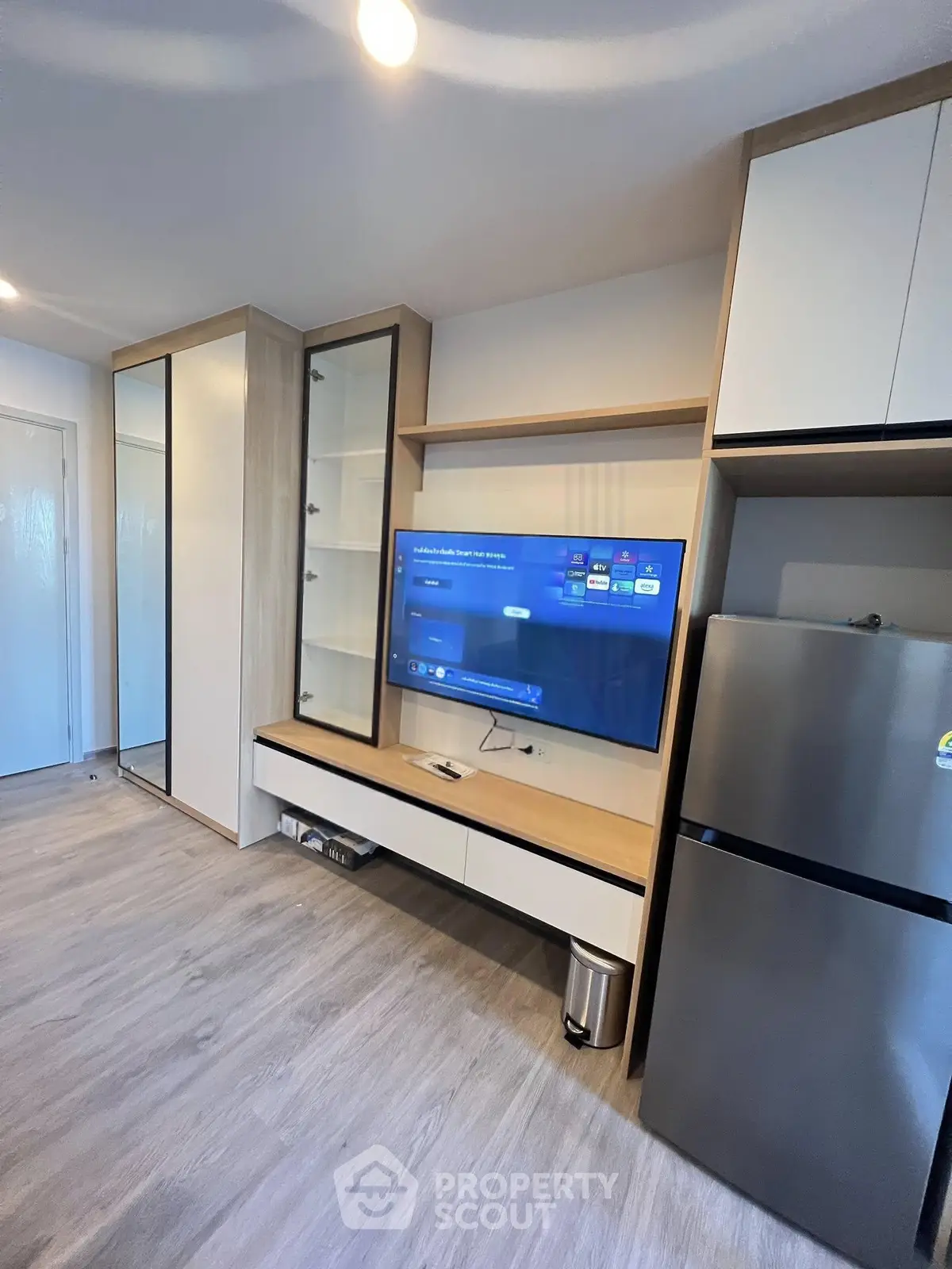 Modern living room with sleek TV setup and stainless steel fridge, perfect for contemporary living.