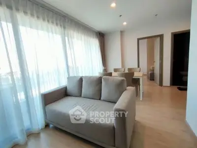 Spacious living room with large windows and modern furniture in a bright apartment.